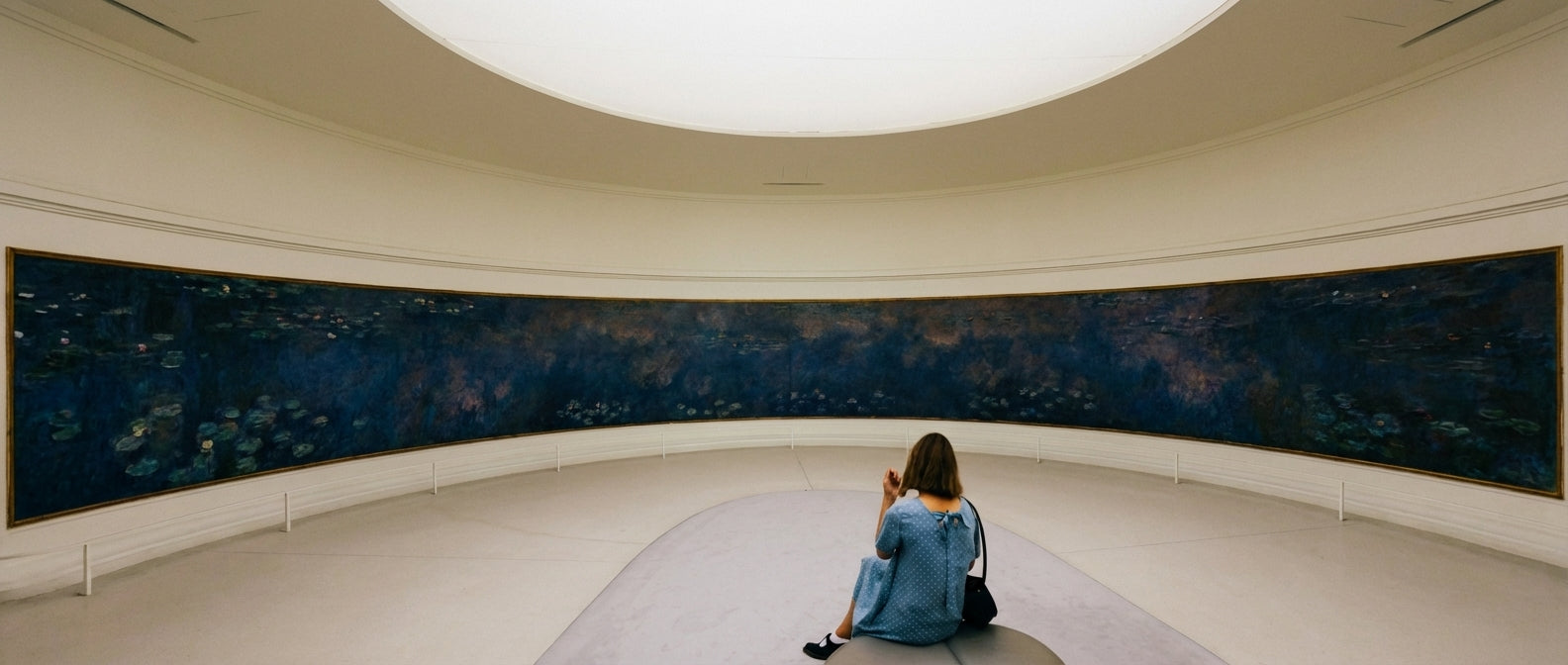 Woman viewing art in a modern gallery, representing the artistic inspiration behind Velvetkay handcrafted press-on nails.