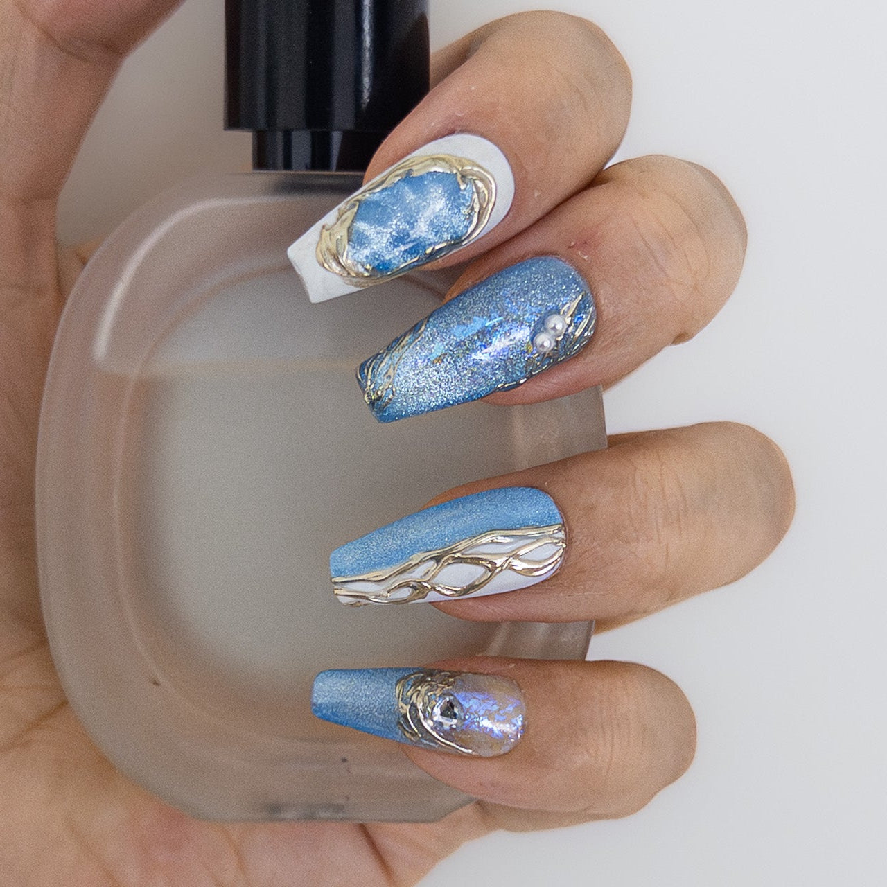 Icy blue marble and gold chrome accents featuring 3D gems on shimmering salon-grade structured gel coffin nails.