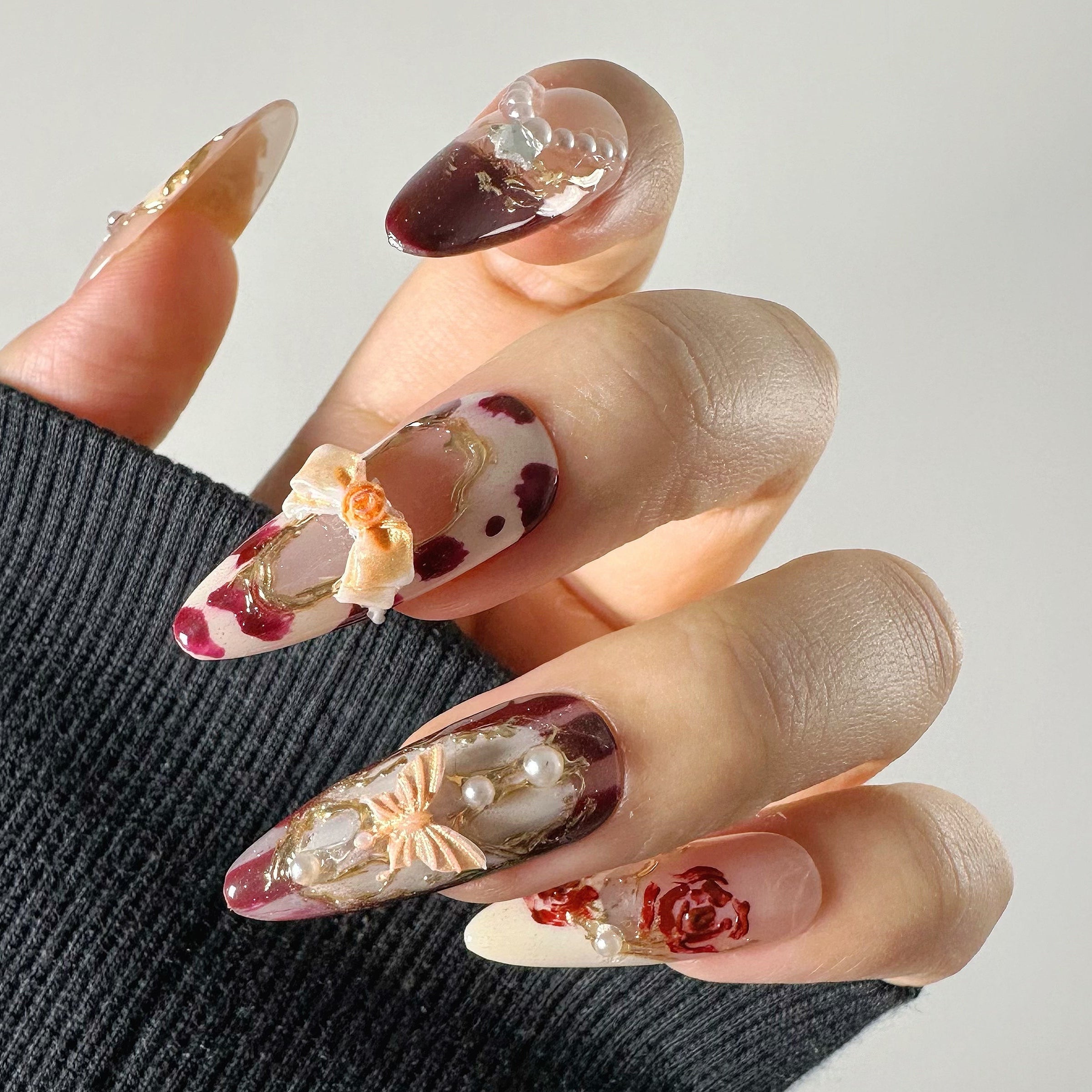 3D beige ribbon and butterfly charms with hand-painted burgundy floral art on multi-layered vintage coquette structure gel.