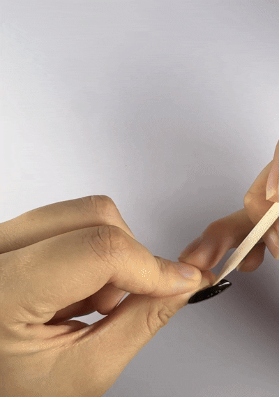 Using the cuticle pusher from the Velvetkay tool kit to gently lift the press-on nail edge.