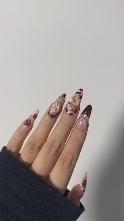 Coquette style burgundy and vintage rose art featuring 3D pearl chains and gold bows on handcrafted almond gel press-on nails by Velvetkay.