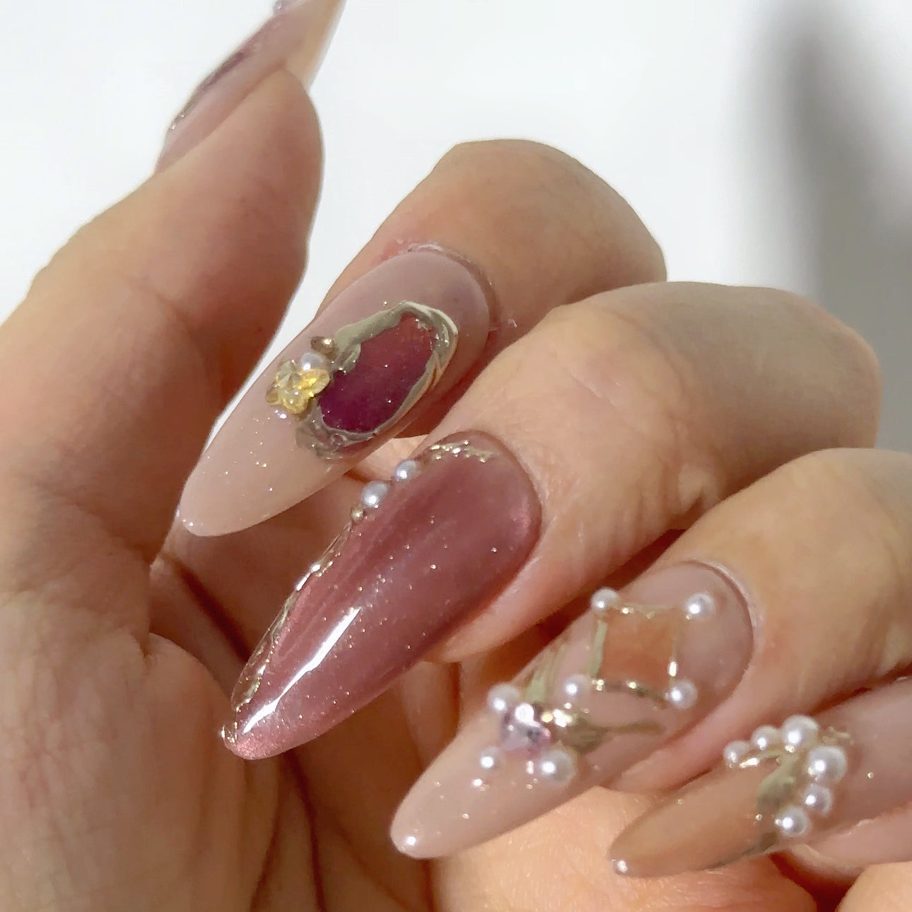 Irregular gold border encasing amber gemstone on glossy mauve magnetic cat-eye structured gel.