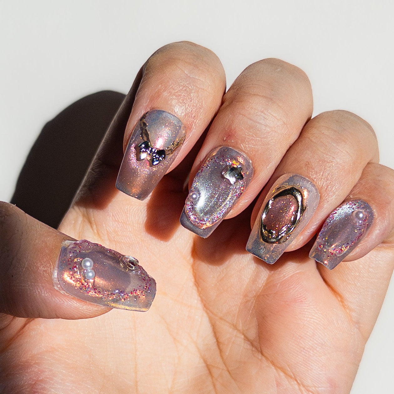 Macro shot of 3D Saturn charm and black bow on shimmering magnetic lavender salon-grade structured gel nails.