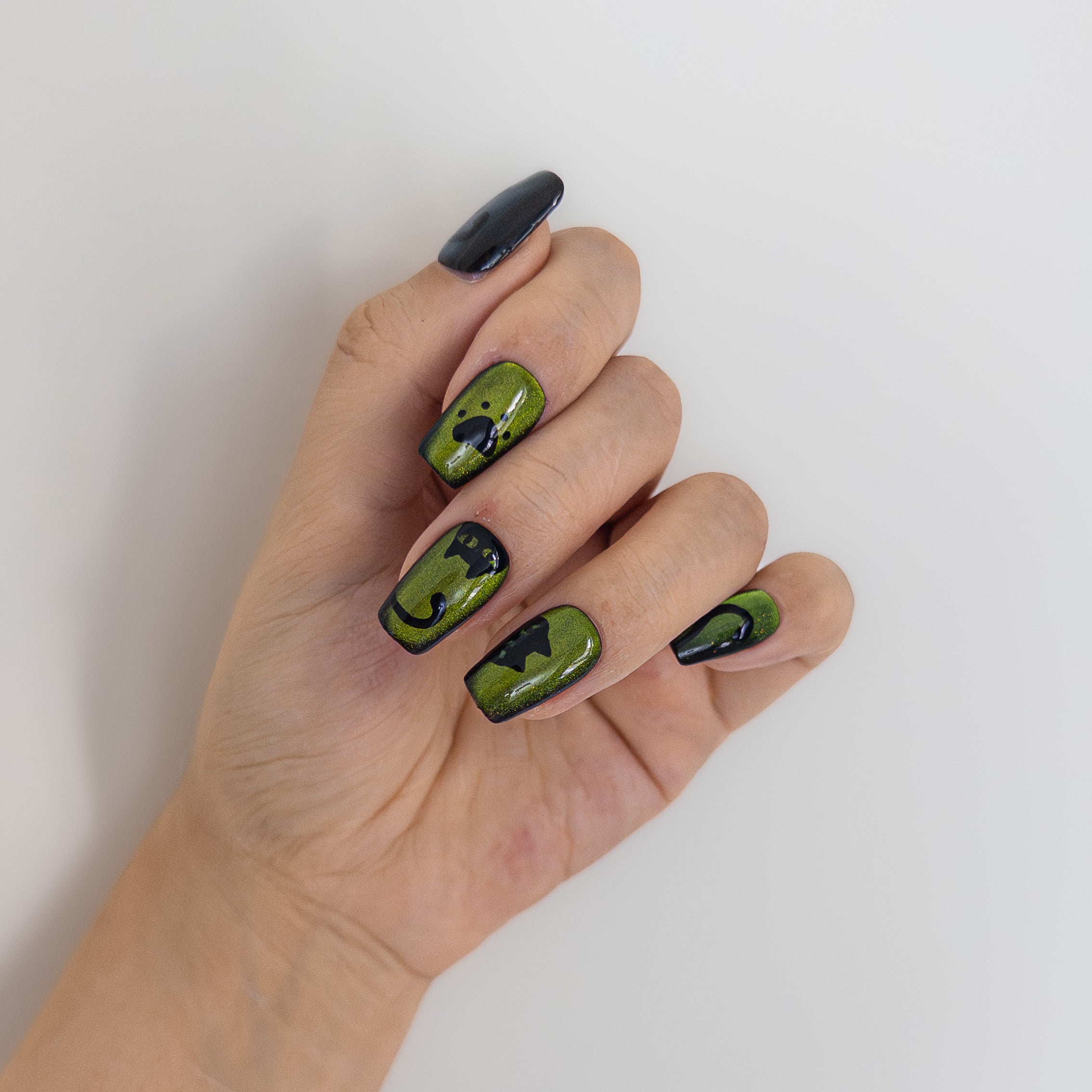 Close-up of high-gloss green velvet cat-eye texture and custom black cat details on durable reusable sculpted gel nails.