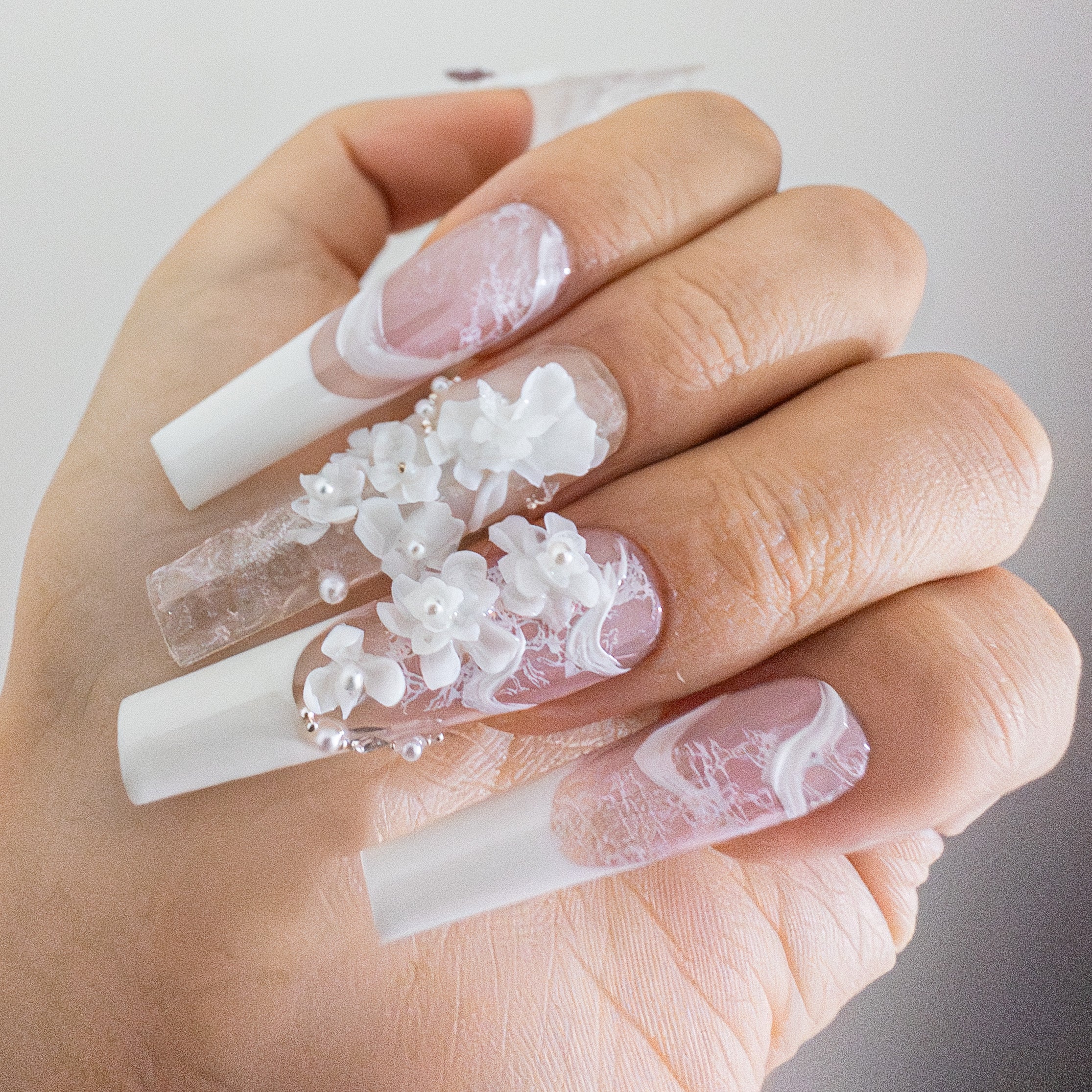 Detailed shot of a sculpted purple butterfly charm and textured white 3D artistry on a clear luxury press-on nail.