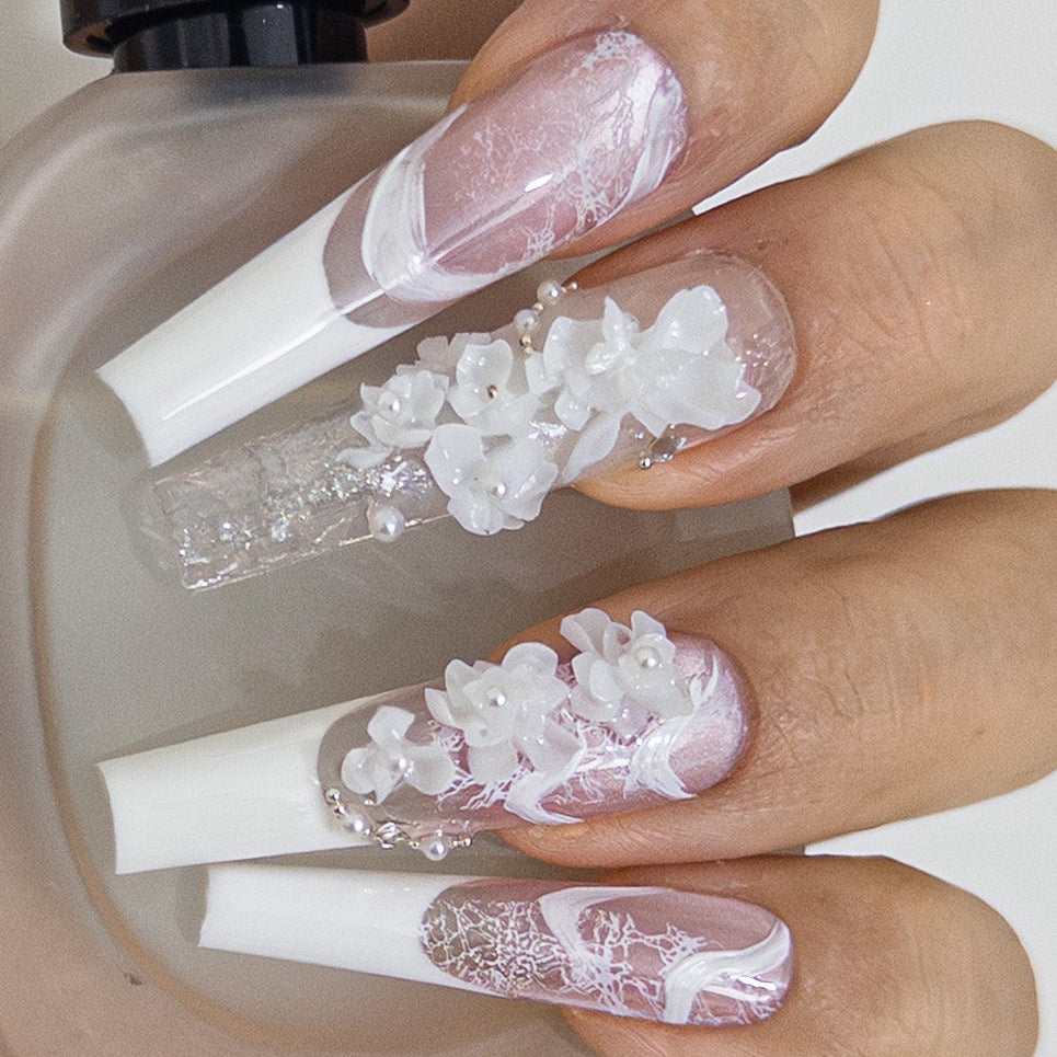 Close-up of long coffin press-on nails featuring white lace French tips and clustered 3D white flowers with delicate pearl accents.