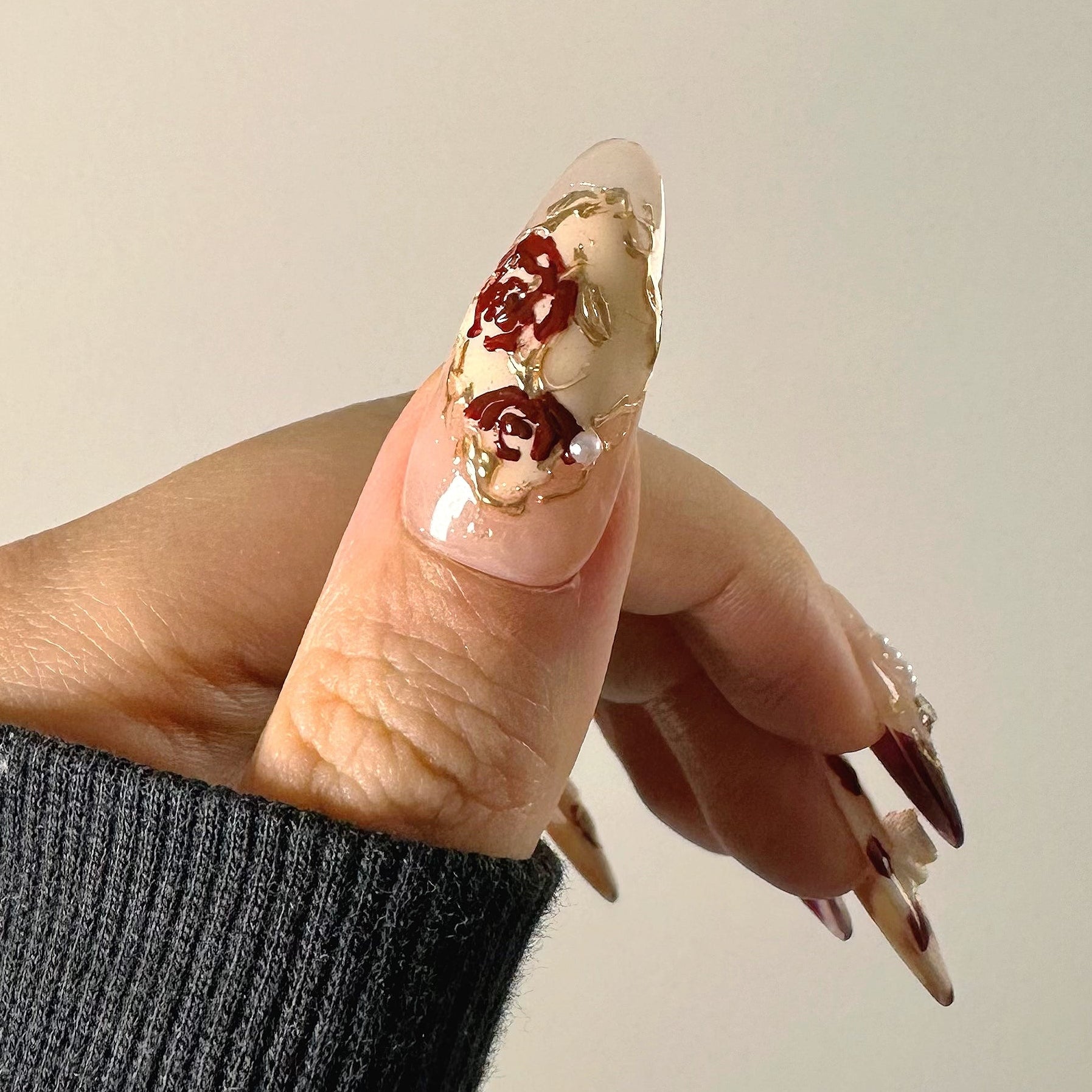 Hand-painted antique burgundy rose art with gold chrome vines and pearl accents on nude structure gel.